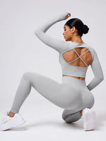 Person wearing a gray athletic outfit with criss-cross back design on a white background