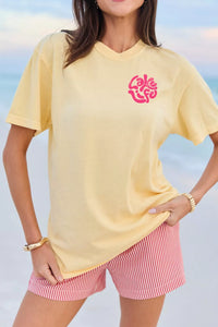 Woman wearing a yellow t-shirt with a pink logo and red and white striped shorts against a blue sky.