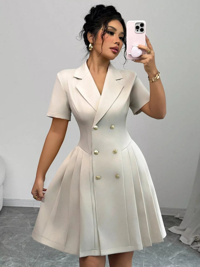 Woman taking a mirror selfie wearing a beige blazer dress against a plain background