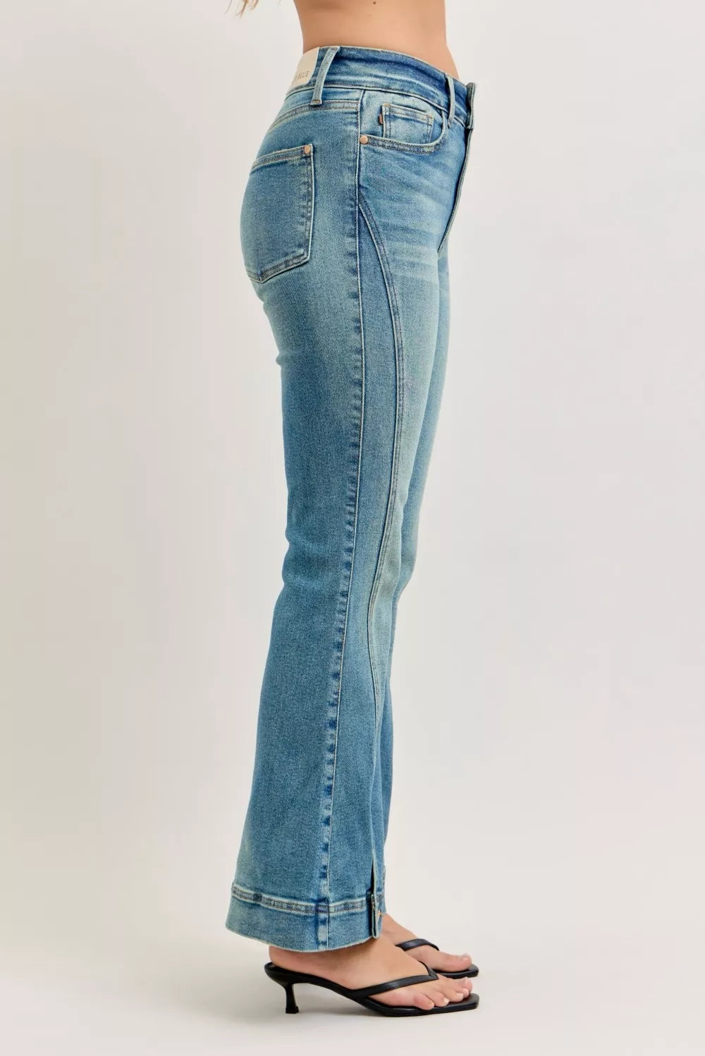 Blue jeans worn by a person on a plain background