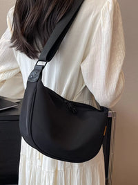 Person wearing a black shoulder bag with a neutral background