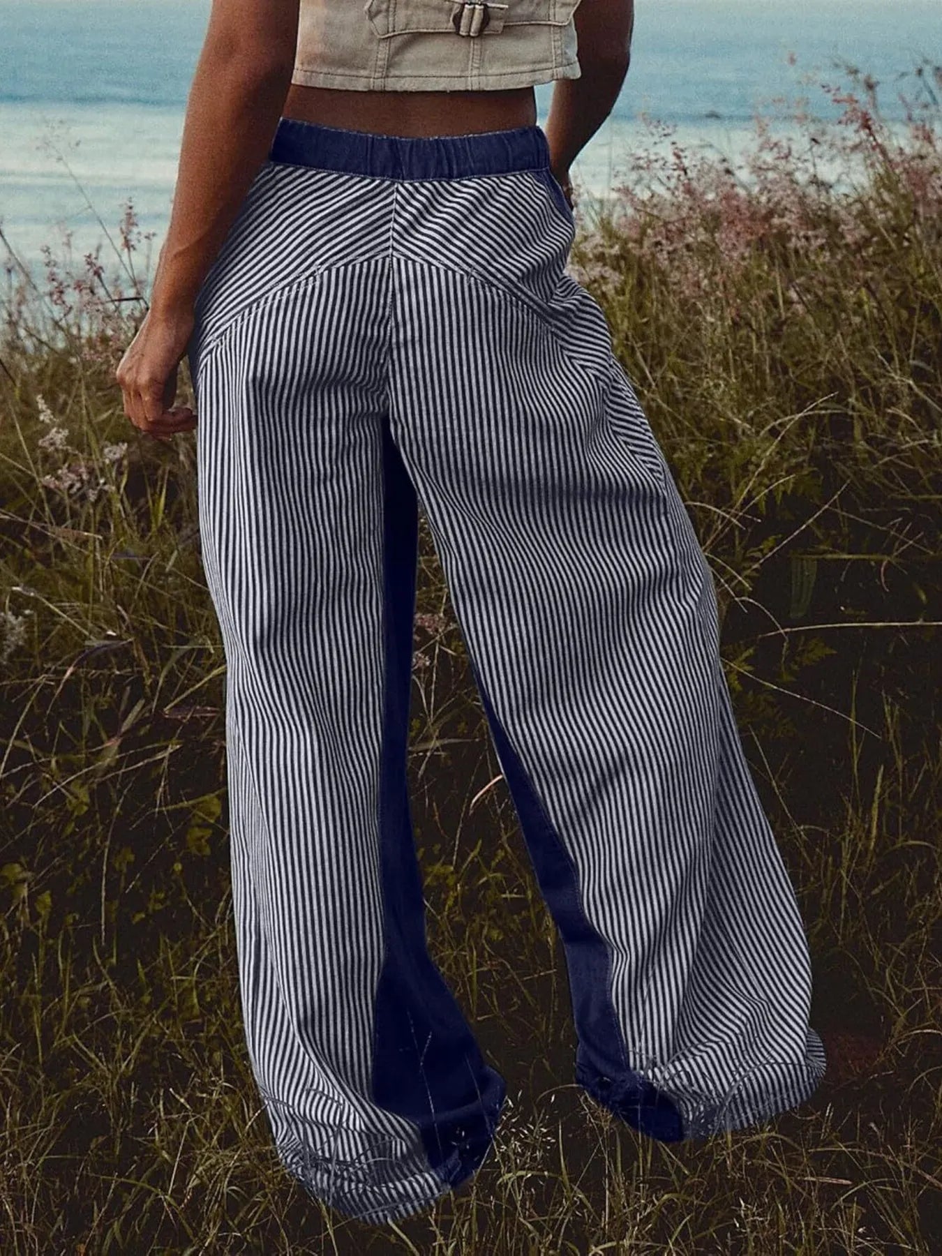 Person wearing blue and white striped pants standing in a field with a blurred background