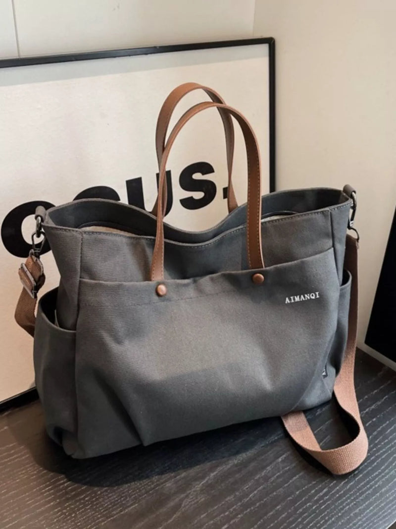 Gray tote bag with brown straps on a wooden surface