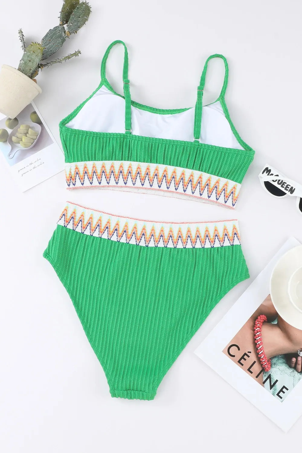Green ribbed swimsuit with colorful trim on a white surface.