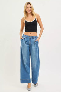 Woman wearing a black tank top and blue jeans on a white background