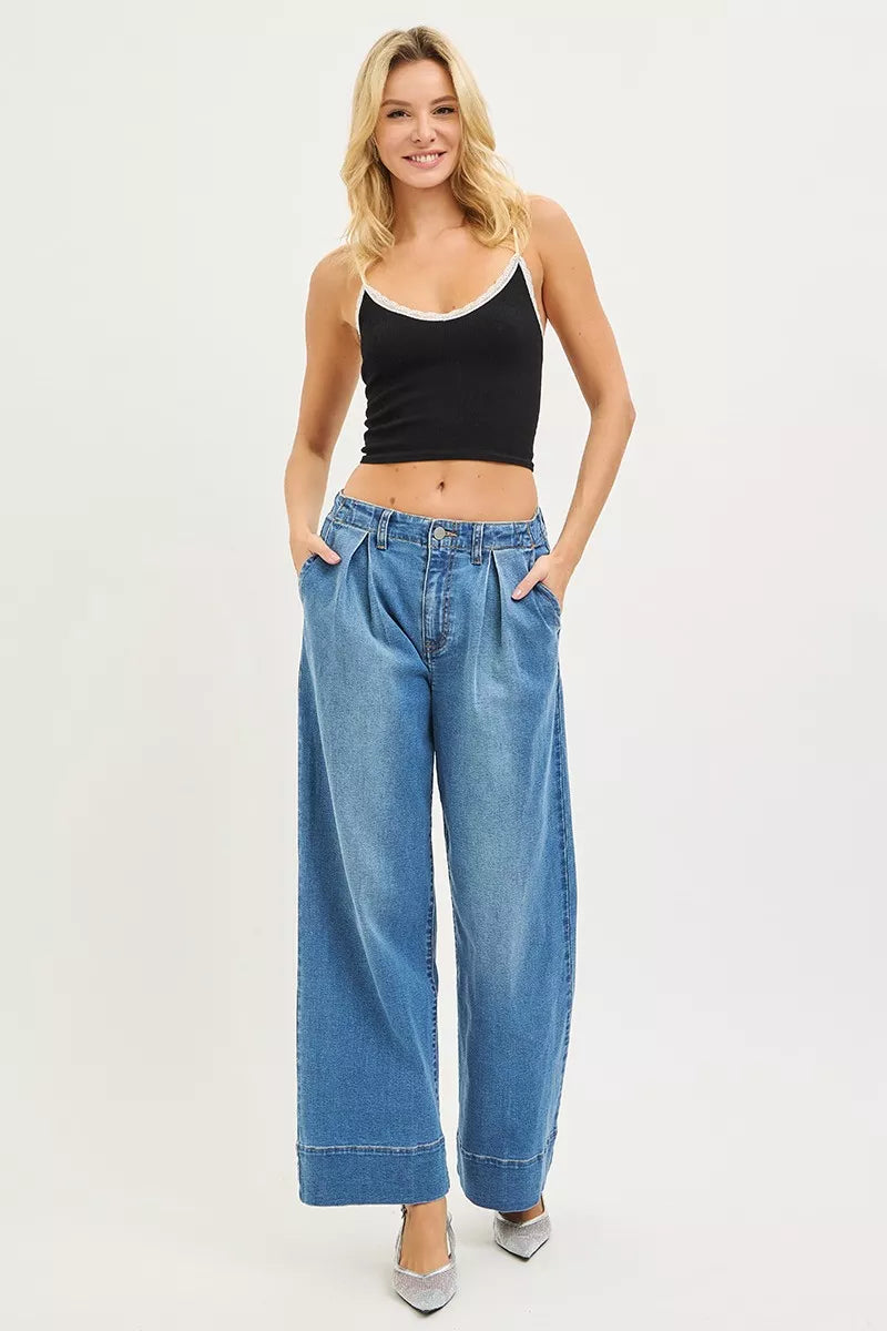 Woman wearing a black tank top and blue jeans on a white background