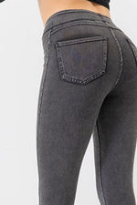 Gray jeans being worn on a plain background