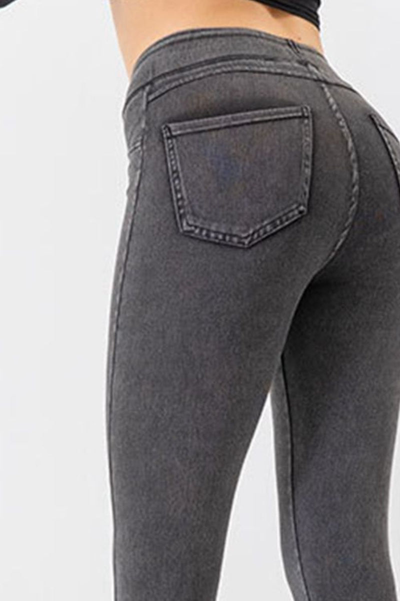 Gray jeans being worn on a plain background