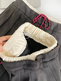 Close-up of gray pants with a white lining and red drawstring.