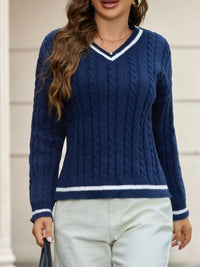 Woman wearing a blue cable knit sweater with white trim.