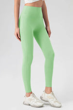 Person wearing green leggings and white sneakers on a plain background
