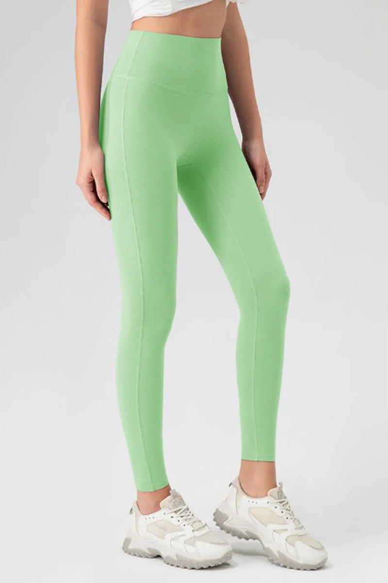 Person wearing green leggings and white sneakers on a plain background