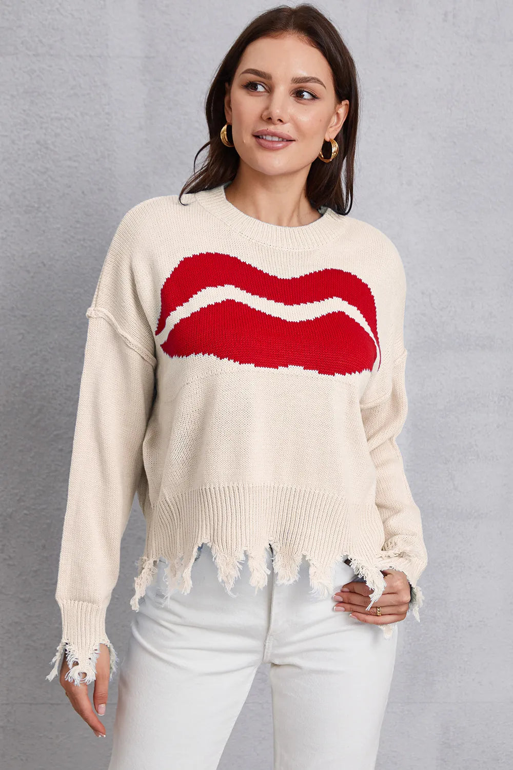 Woman wearing a cream sweater with a red and white graphic design on a gray background