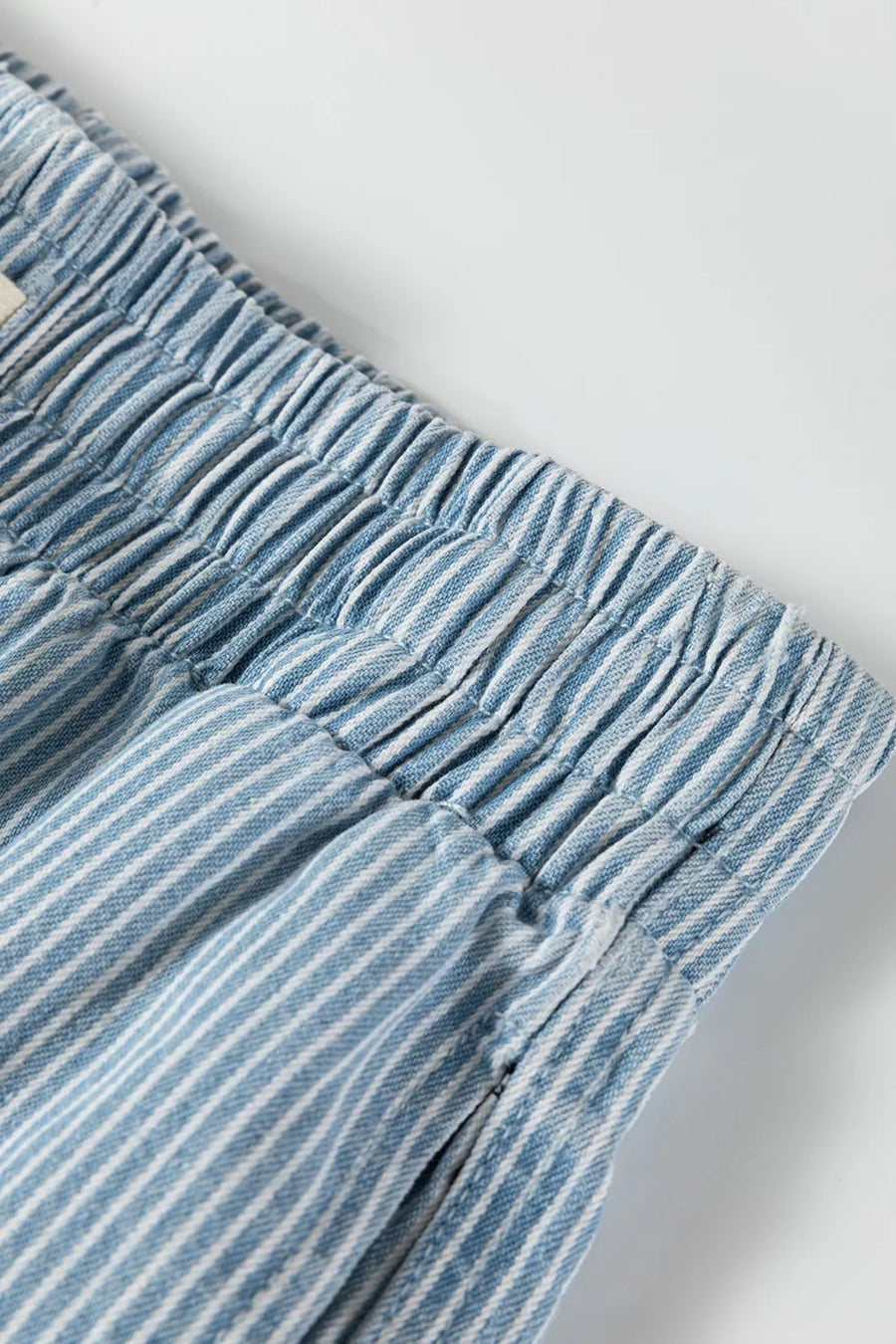 Close-up of blue striped pants with an elastic waistband on a light gray background