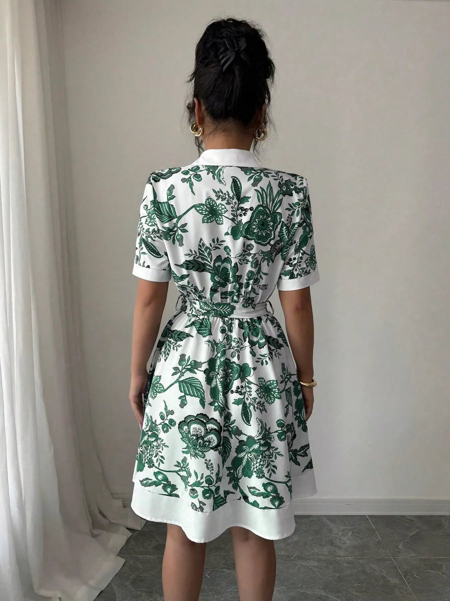 Person wearing a white dress with green floral pattern in a minimal indoor setting