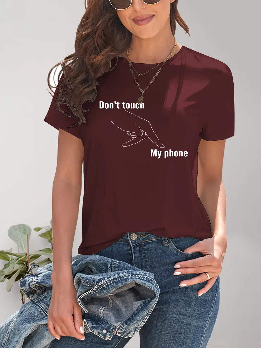 Person wearing a maroon t-shirt with 'Don't touch my phone' text and gesture design.