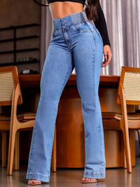 Person wearing high-waisted blue jeans in a casual setting with wooden chairs and a neutral background.