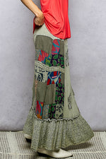 Person wearing a colorful patchwork skirt with a plain background