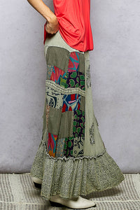 Person wearing a colorful patchwork skirt with a plain background