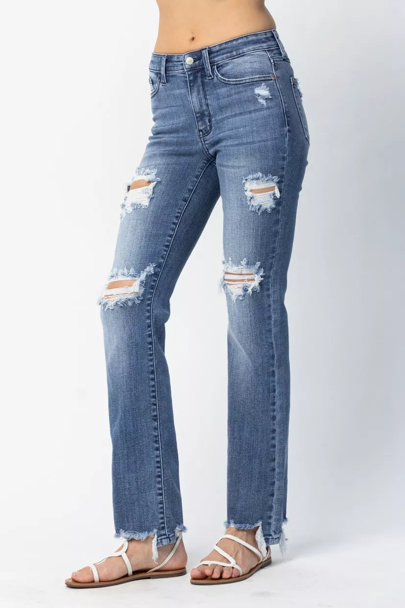 Distressed blue jeans worn by a person on a white background