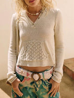 Person wearing a light-colored sweater with lace detailing and colorful pants.