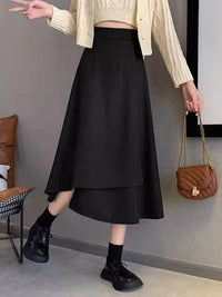 Person wearing a black skirt and beige sweater in an indoor setting