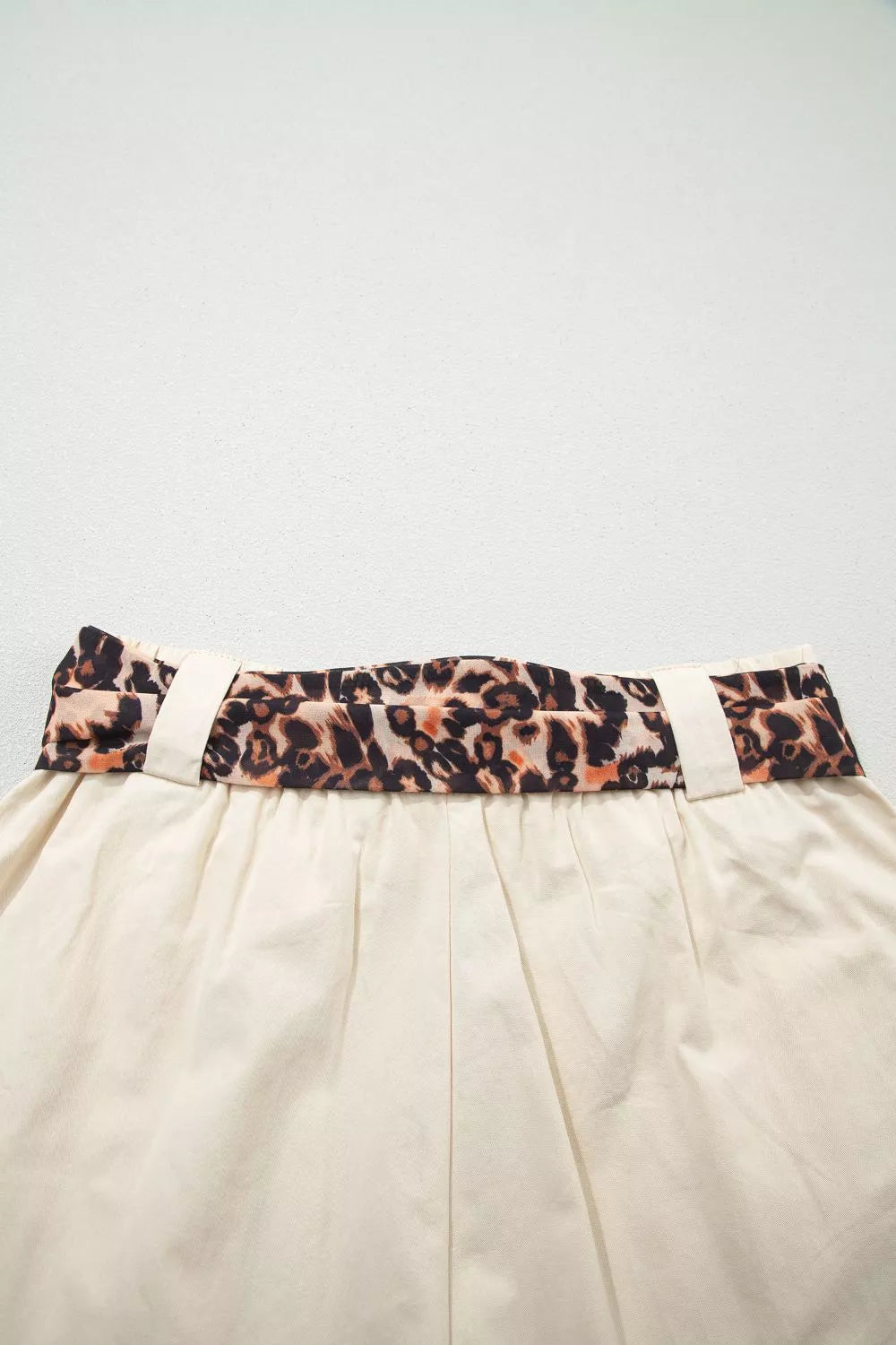 Beige skirt with a leopard print belt on a light gray background