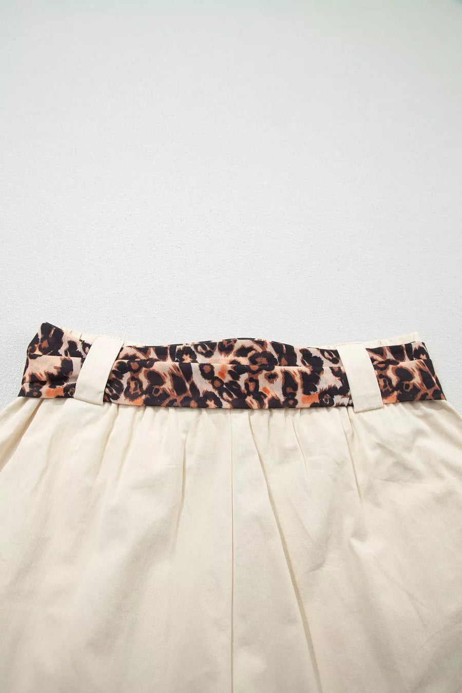 Beige skirt with a leopard print belt on a light gray background