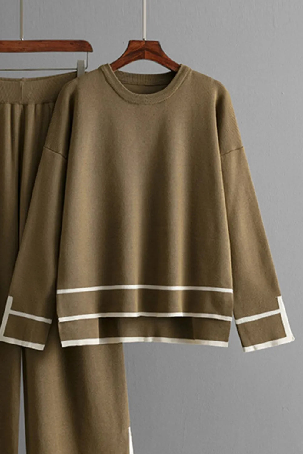 Brown outfit with white stripes on a hanger against a gray background