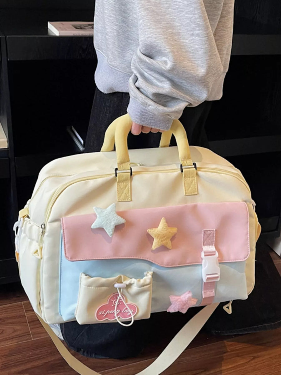 Pastel-colored bag with star designs held by a person wearing a gray sweater.