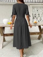 Woman wearing a black dress standing in front of a wooden table with fruit.