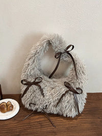 Fluffy white pet collar with brown bows on a wooden surface.