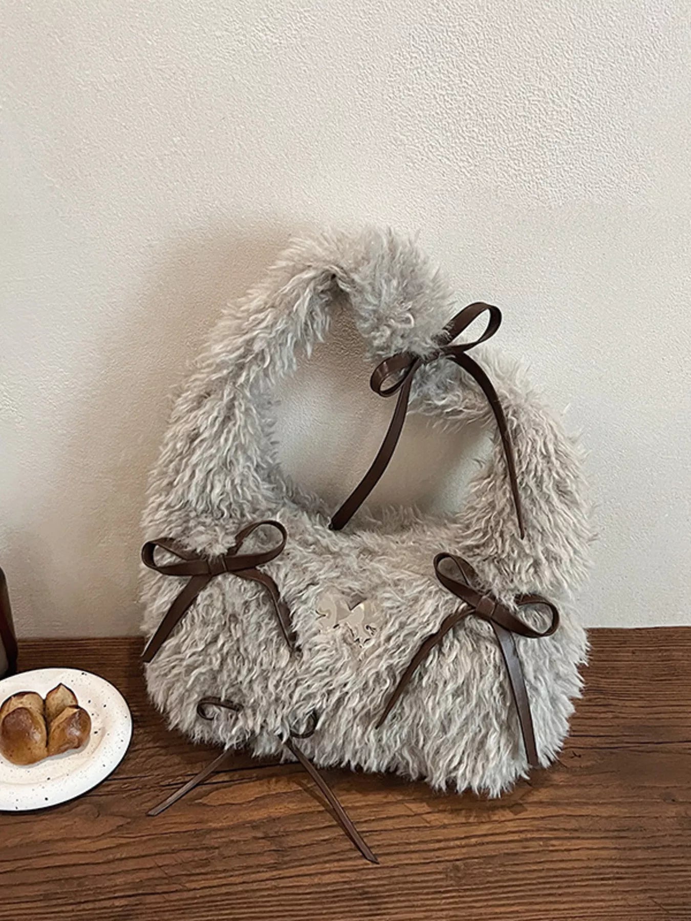 Fluffy white pet collar with brown bows on a wooden surface.