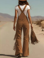Person wearing brown fringed overalls and white top in a desert setting