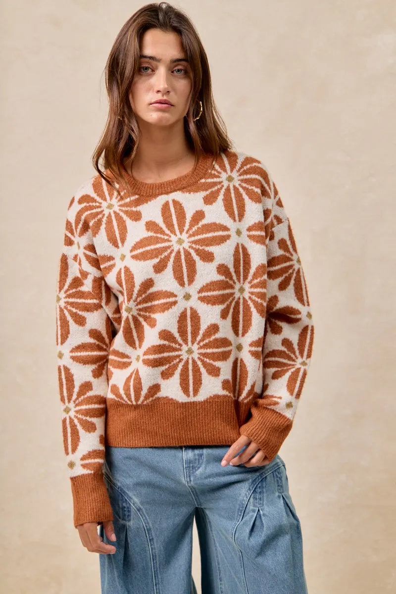 Woman wearing a patterned sweater and jeans against a beige background