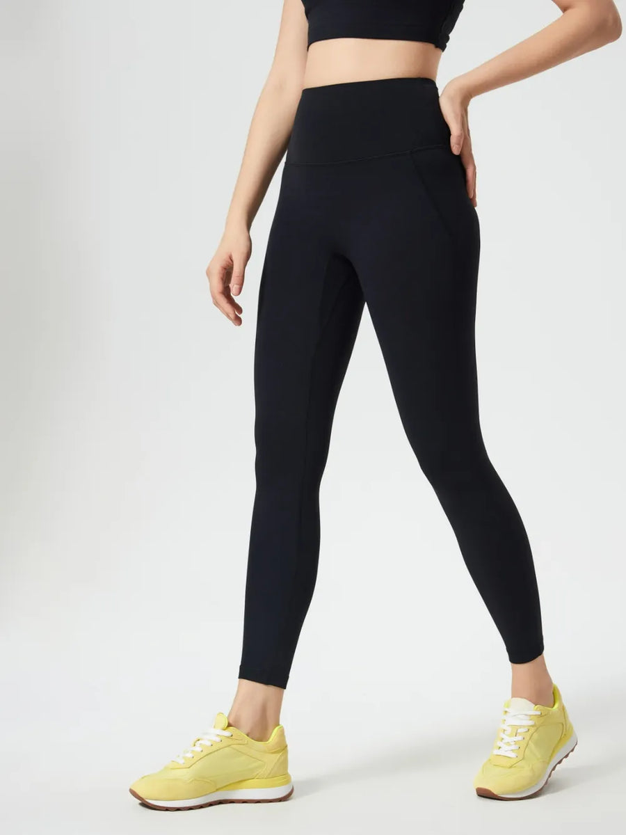 Person wearing black leggings and yellow sneakers on a white background