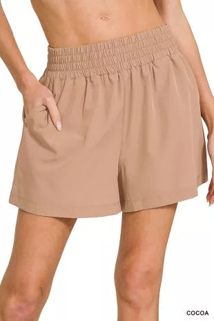 Beige shorts worn by a person on a white background