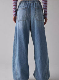 Person wearing blue wide-leg jeans with a plain background