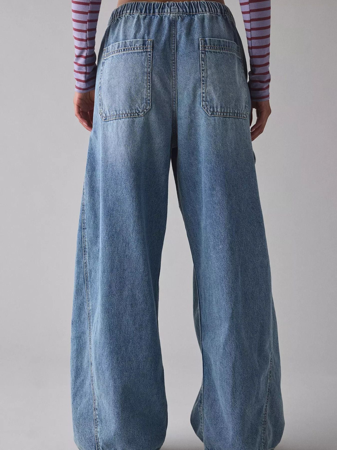 Person wearing blue wide-leg jeans with a plain background