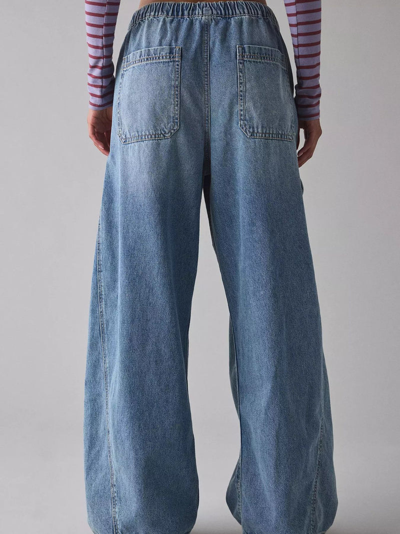 Person wearing blue wide-leg jeans with a plain background
