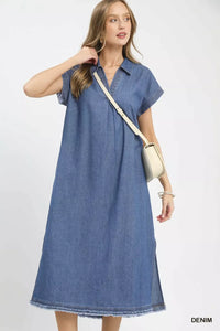 Woman wearing a blue denim dress with a beige bag on a white background