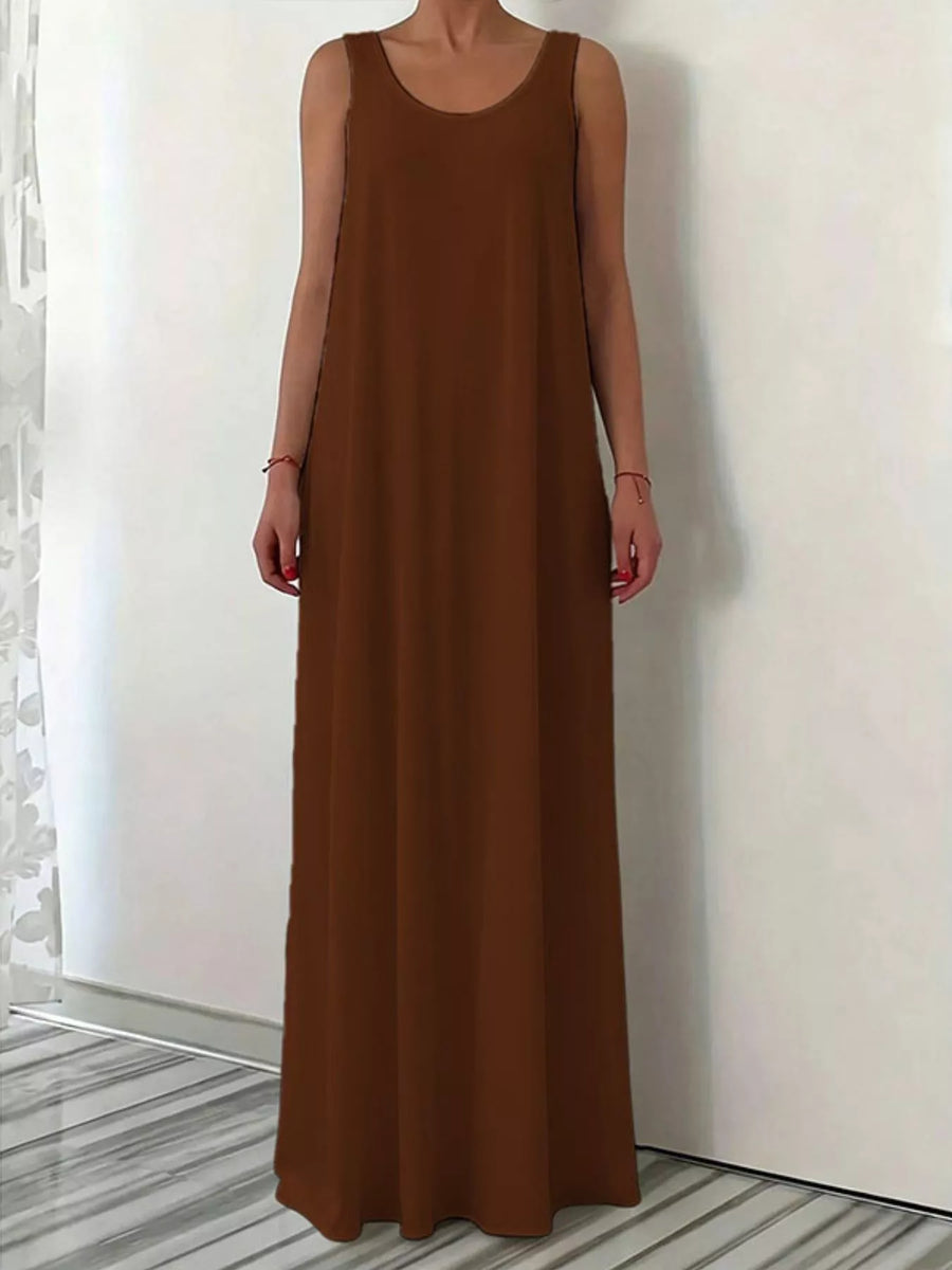 Brown sleeveless dress worn by a person against a white wall.