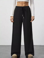 Person wearing black wide-leg pants with a white top on a plain background