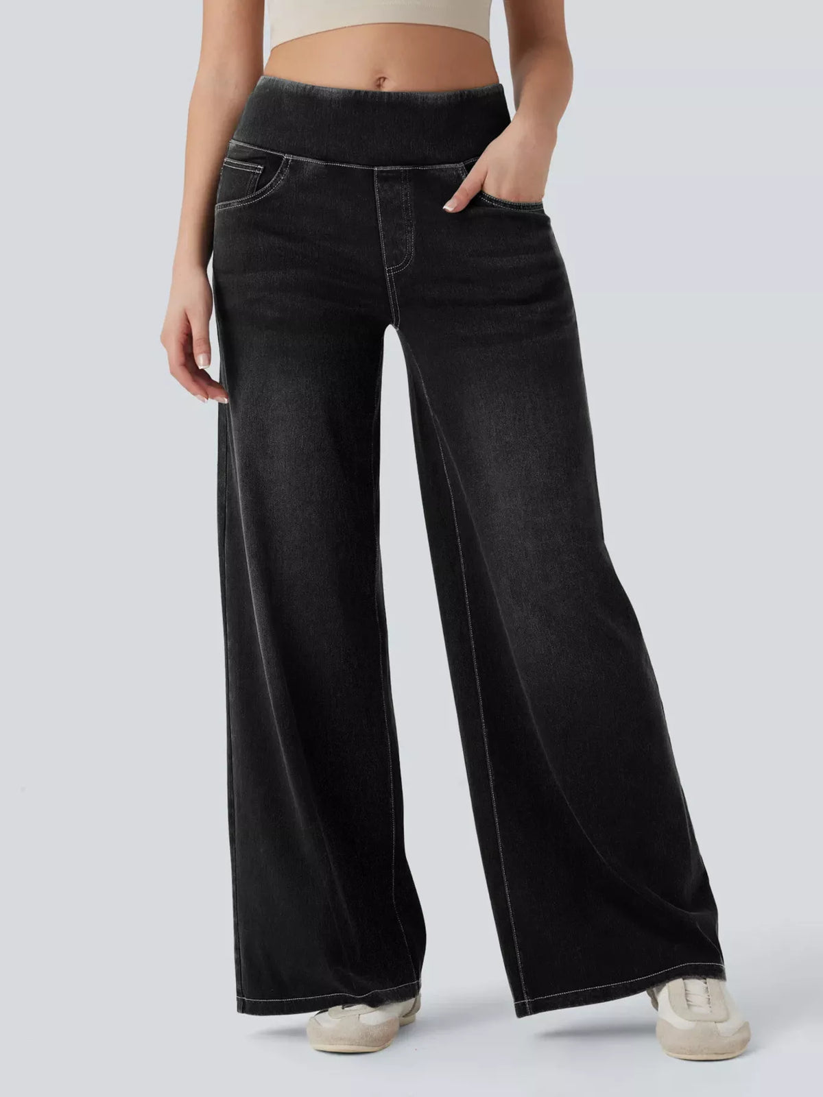 Person wearing black wide-leg jeans on a plain background