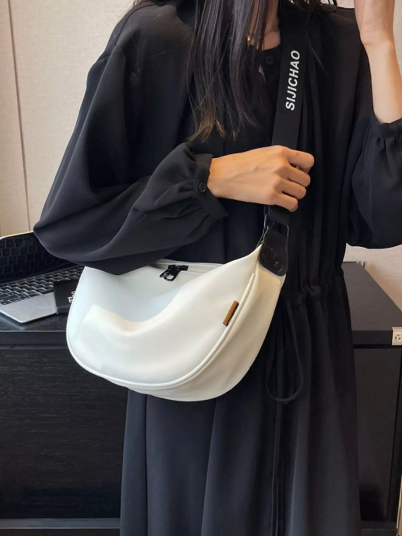 Person holding a white handbag with 'SUICHIAO' branding in an indoor setting.