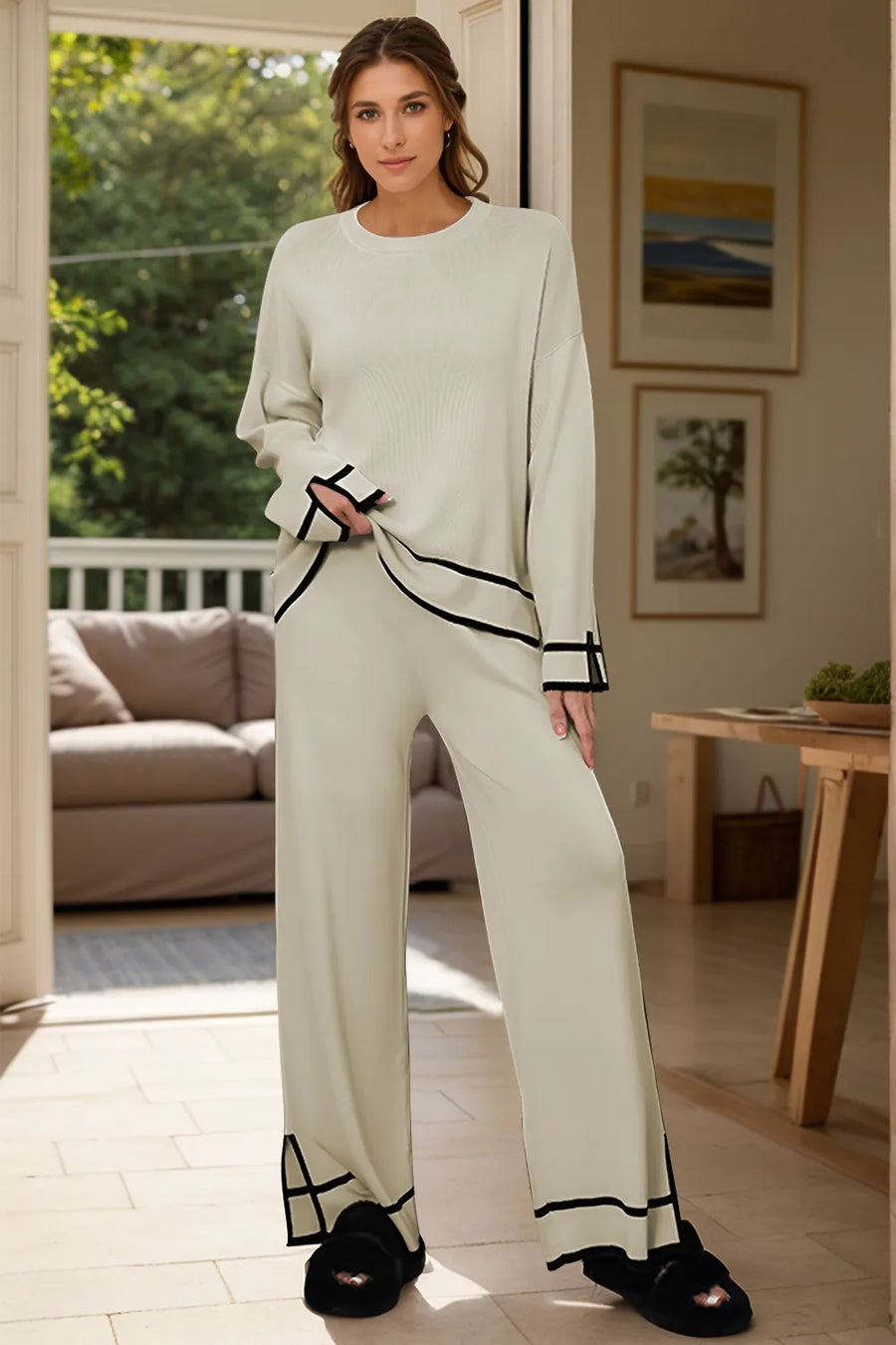 Woman in a white outfit with black accents standing in a living room.