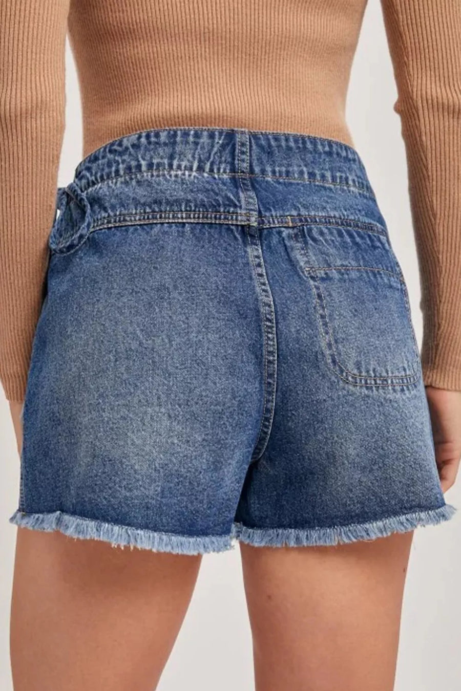 Blue denim shorts worn by a person on a plain background