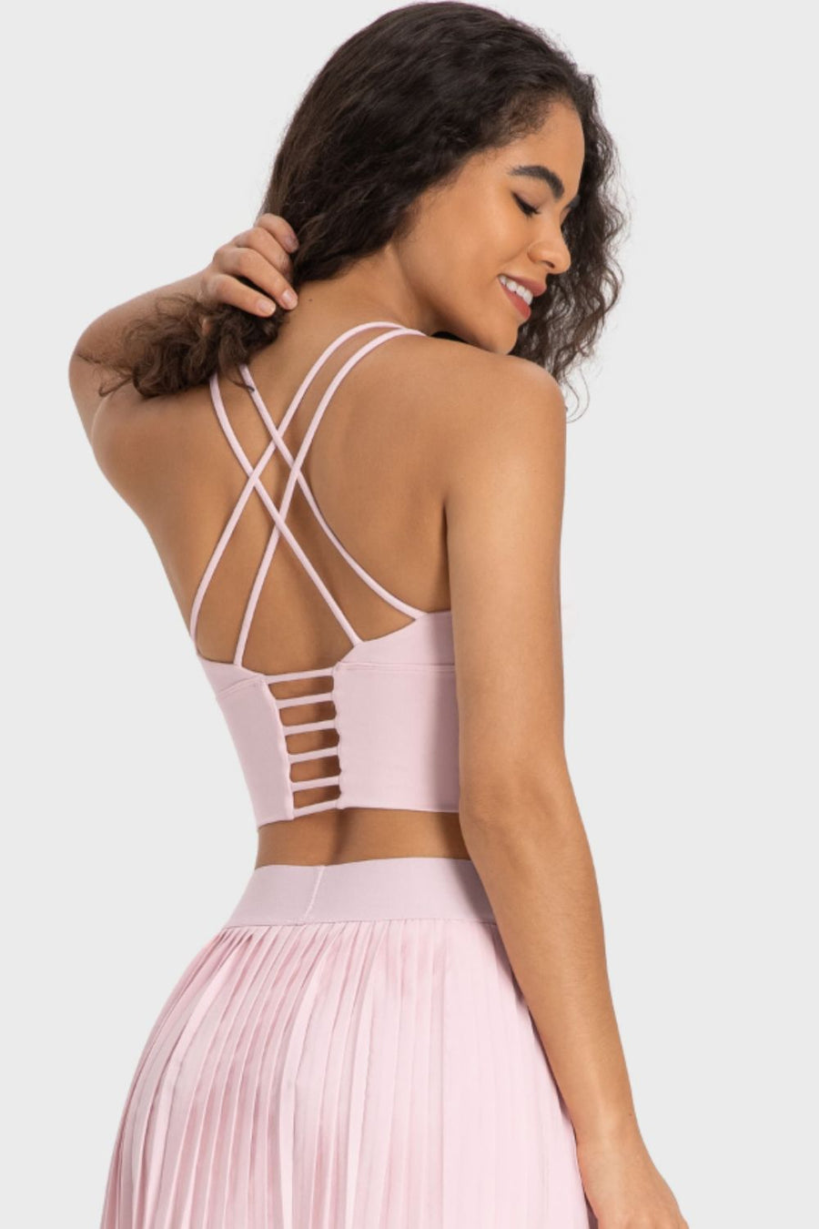Woman wearing a pink dress with a strappy back design on a white background
