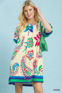 Woman wearing a colorful patterned dress against a light blue background