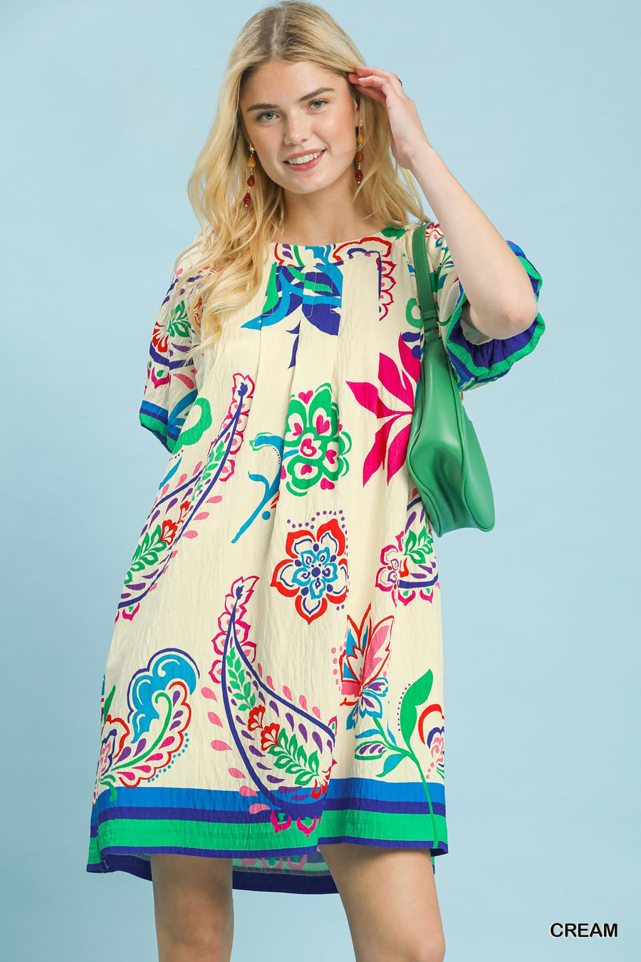 Woman wearing a colorful patterned dress against a light blue background